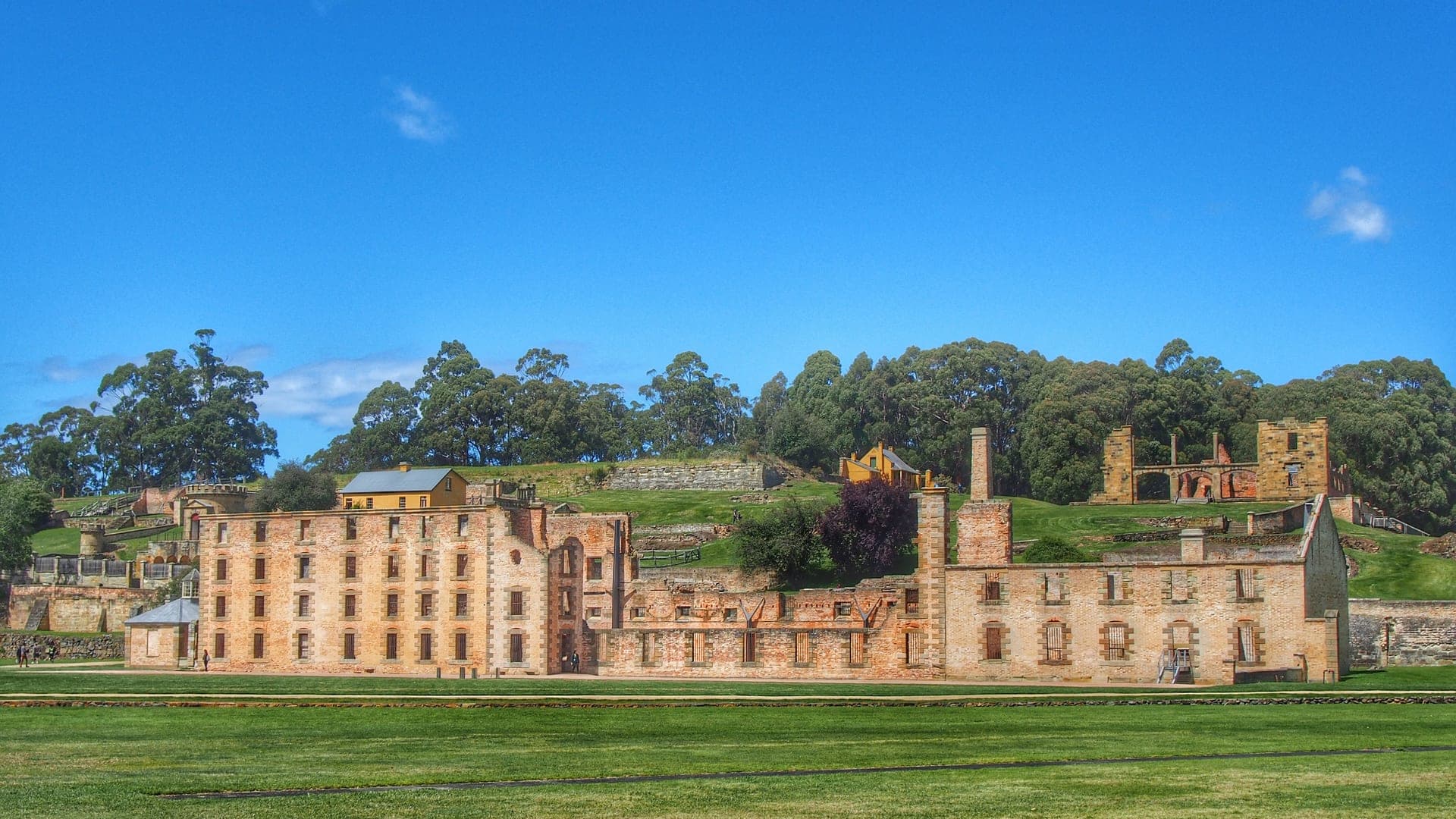 Weathered sandstone penitentiary walls at Port Arthur beside a calm harbour